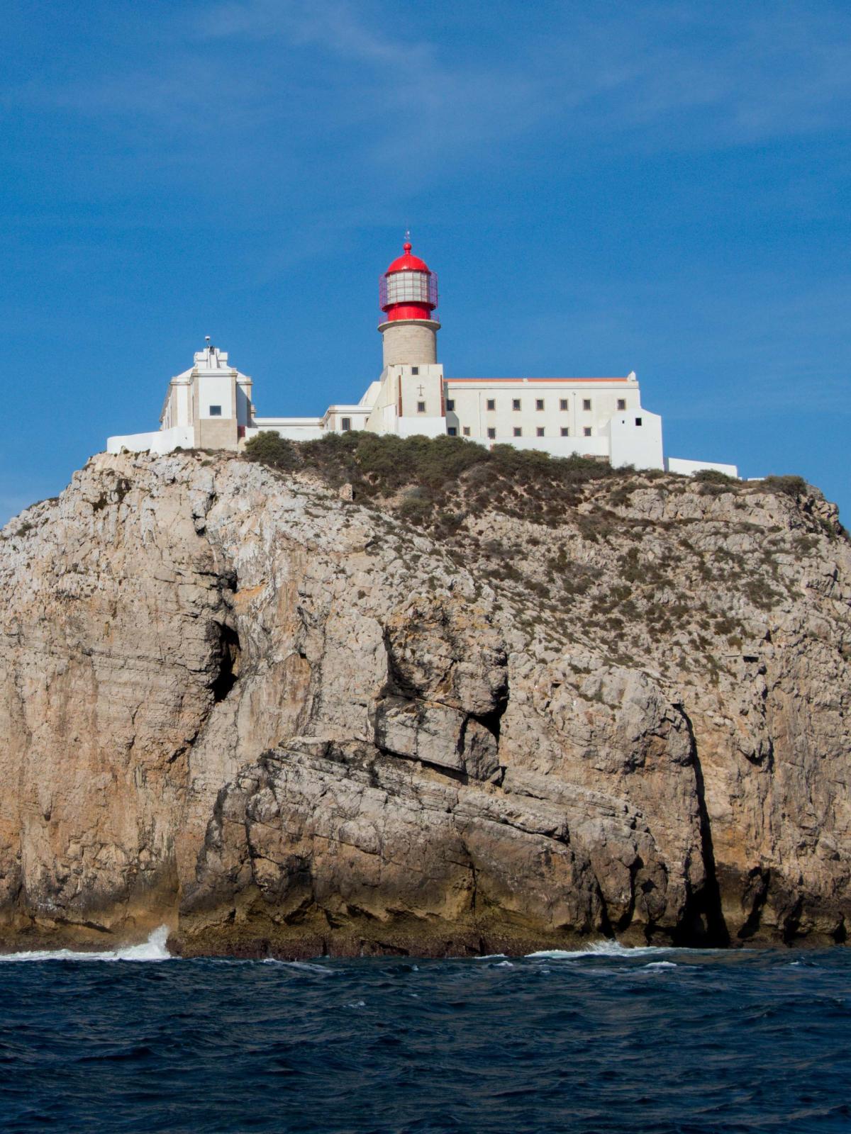 a large building on a cliffside at the back of a body of water