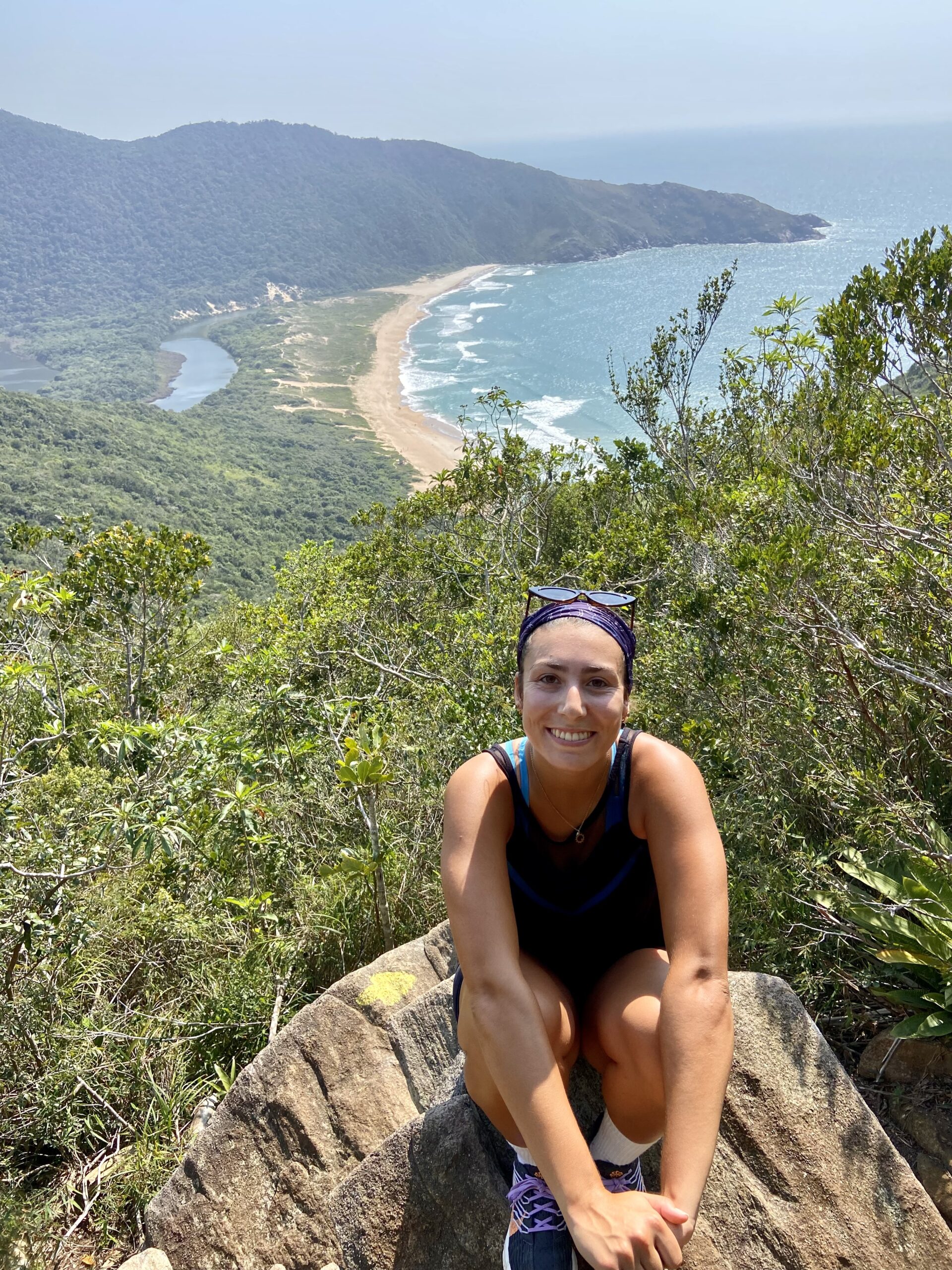 a person sitting on a rock next to a body of water