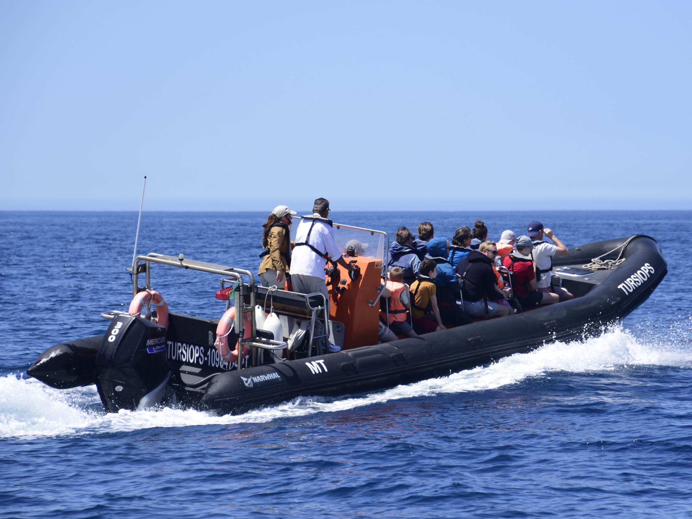a group of people riding on the back of a boat in the water